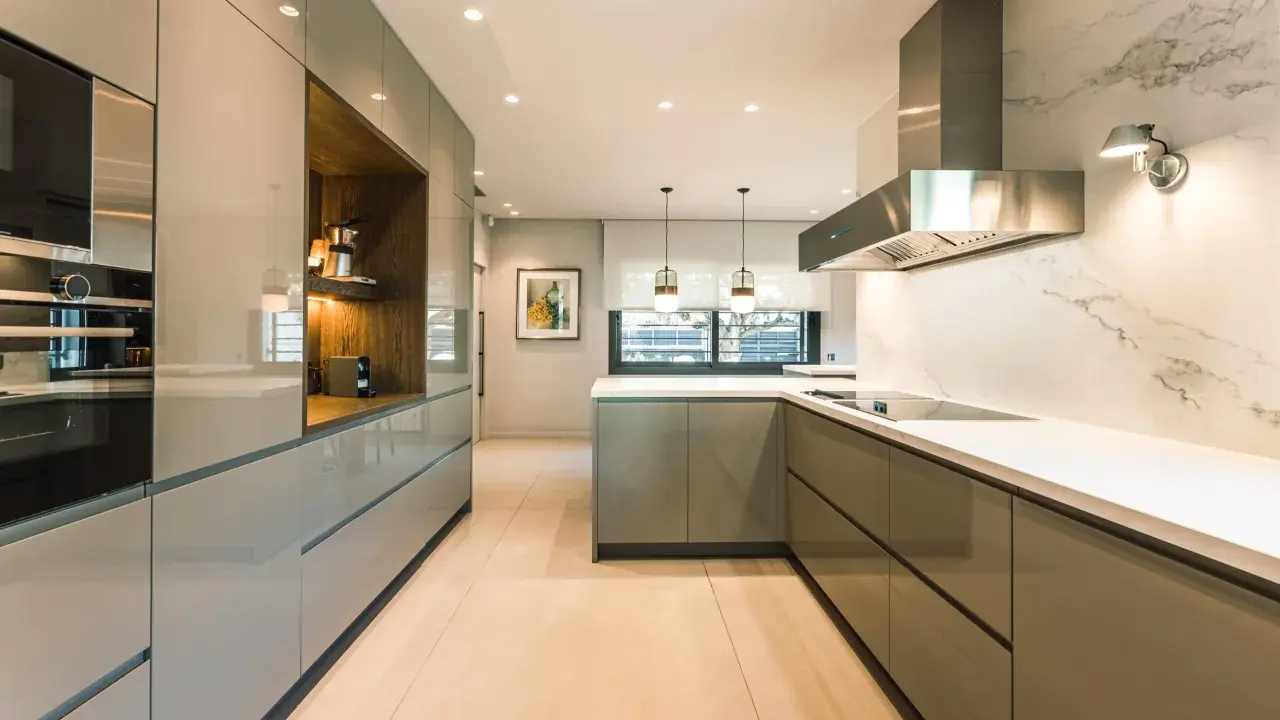 Elegantes diseños de cocinas modernas pequeñas, con gabinetes grises brillantes, encimeras blancas y electrodomésticos integrados.