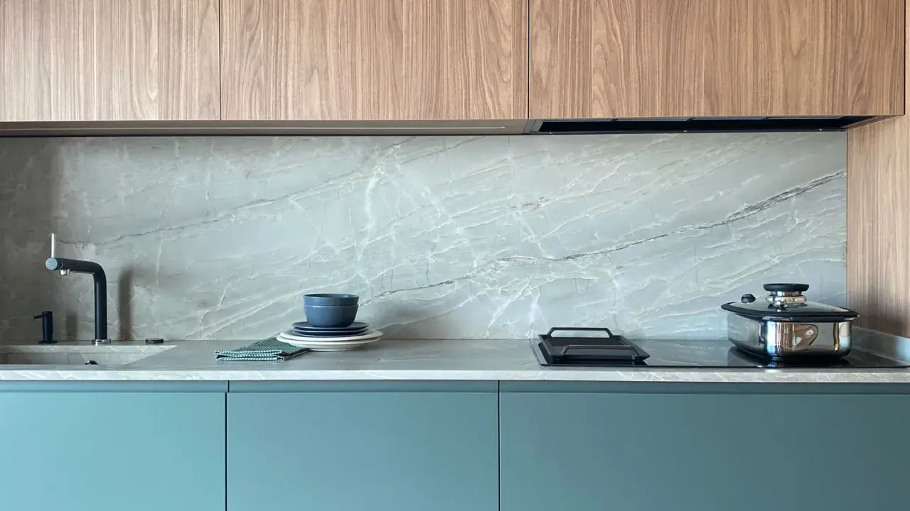 Elegantes gabinetes turquesas y encimeras de mármol gris, perfectos como colores para cocinas pequeñas.