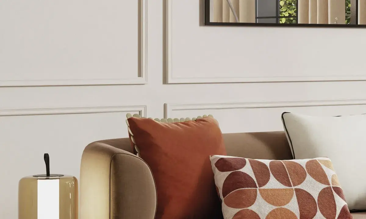 Cojines decorativos de sofá en tonos tierra y un diseño geométrico, junto a una lámpara.