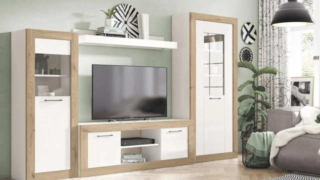 Un moderno salón sin luz natural, con un mueble de TV blanco y madera, una planta y un sofá gris.