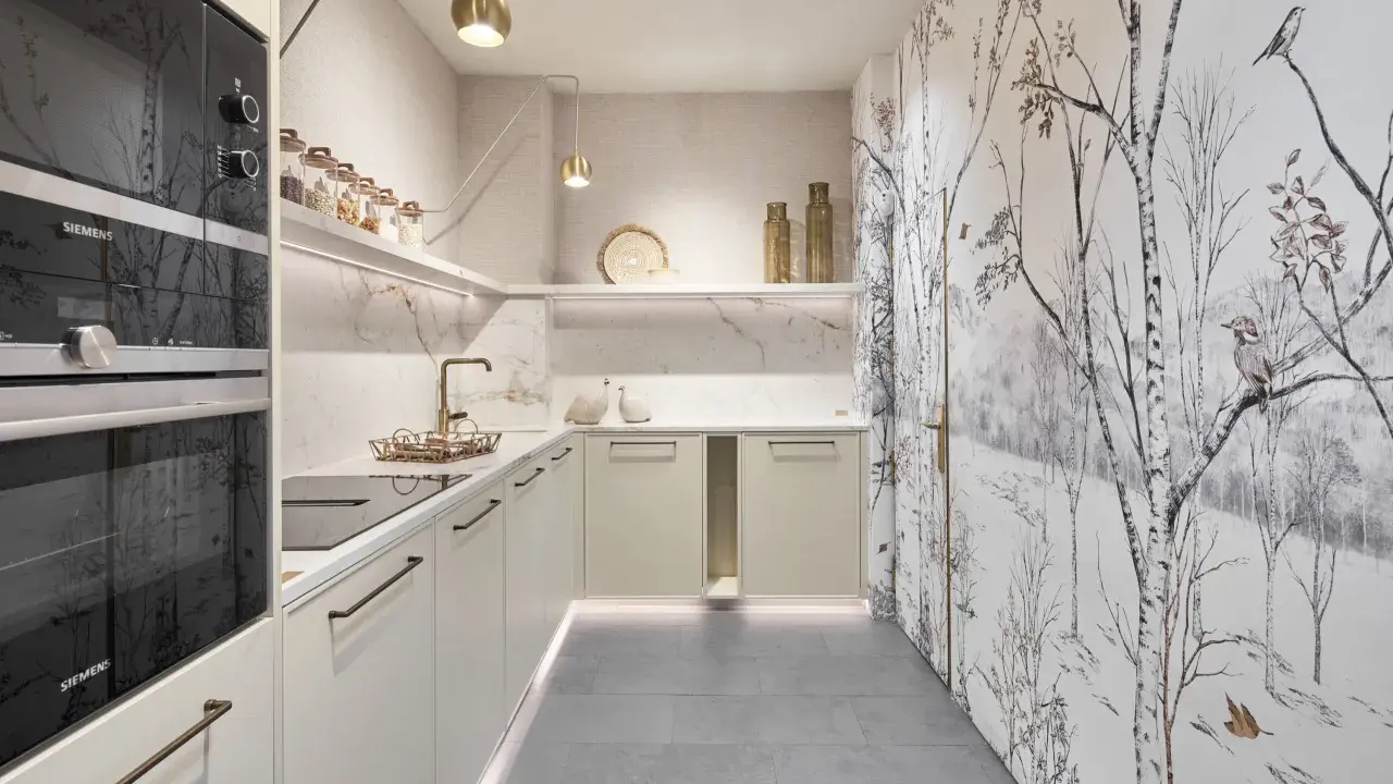 Cocinas pequeñas con encanto: gabinetes color crema, encimeras de mármol, electrodomésticos Siemens y un papel tapiz de bosque invernal.