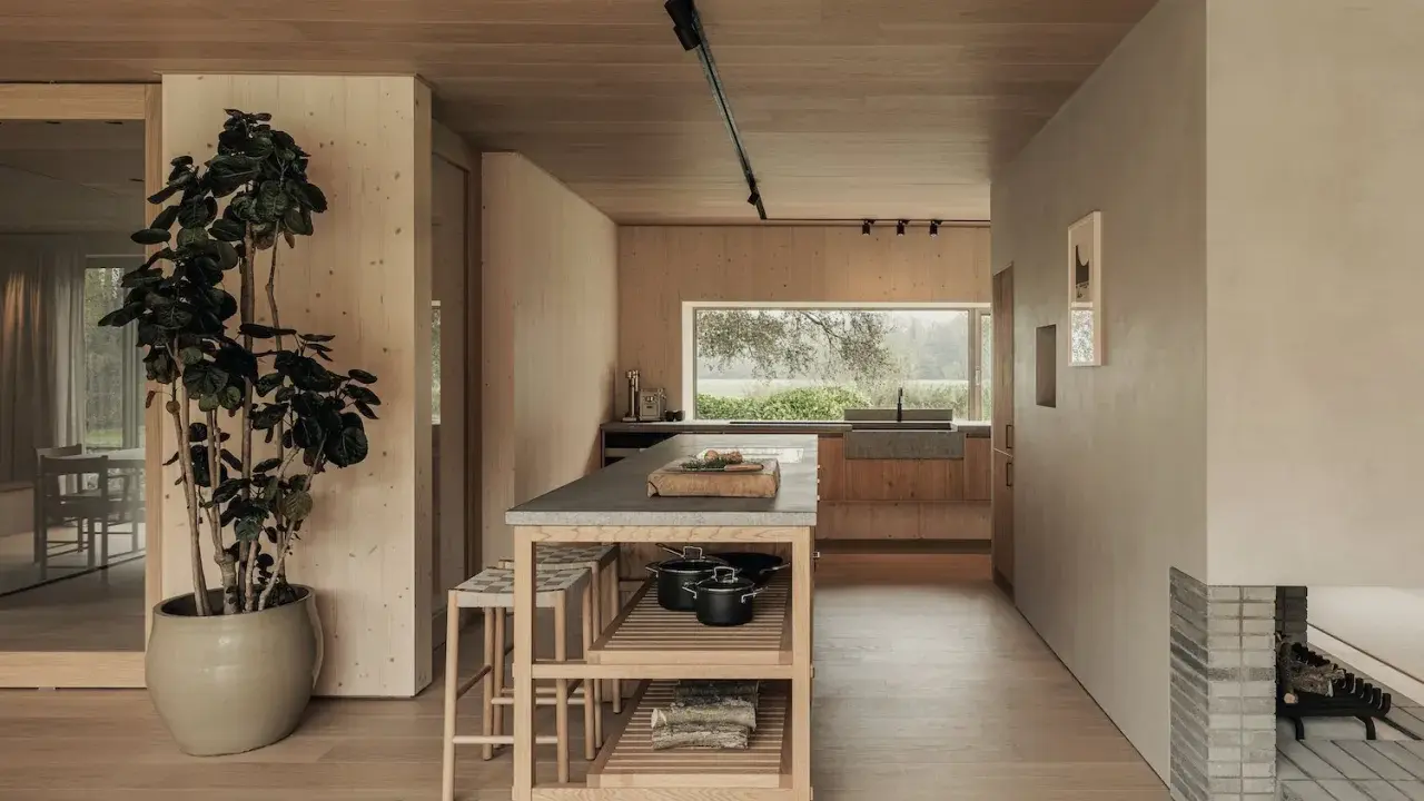 Un acogedor salón cocina pequeño con isla central, mucha madera y una gran ventana al exterior.