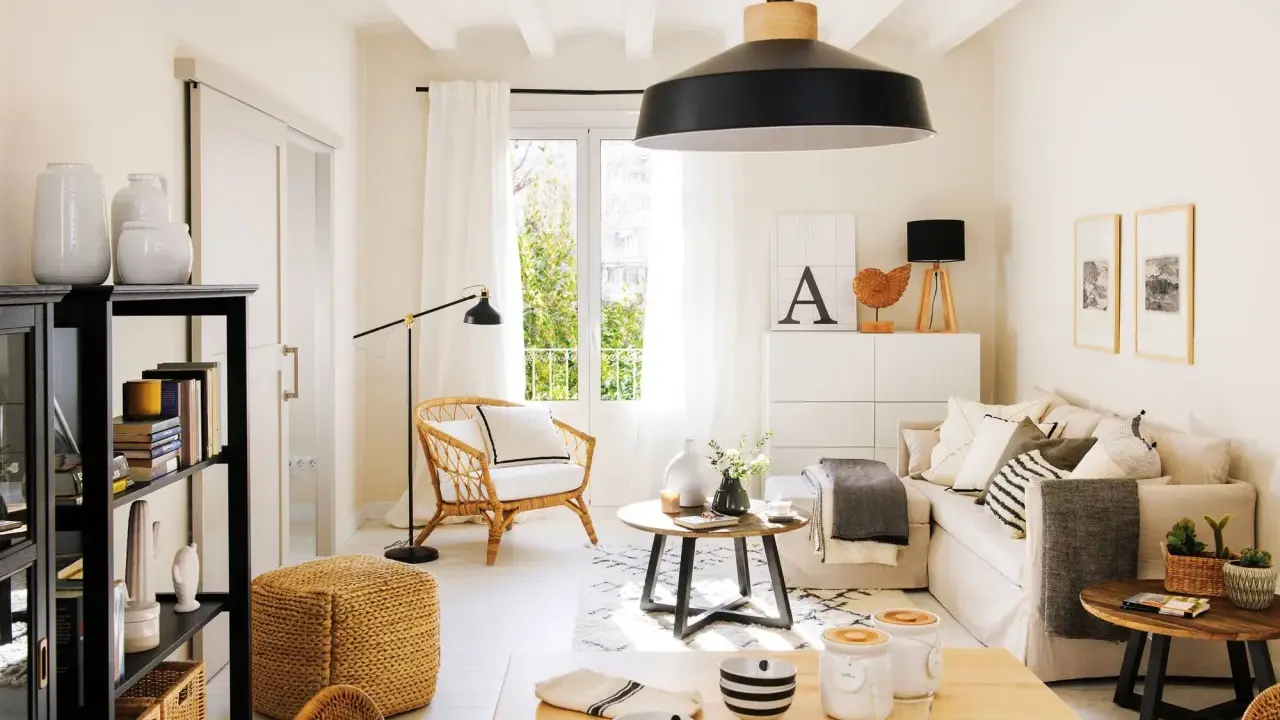 Acogedor salón estilo nórdico con sofá, sillón de mimbre, mesa de centro y estantería negra.