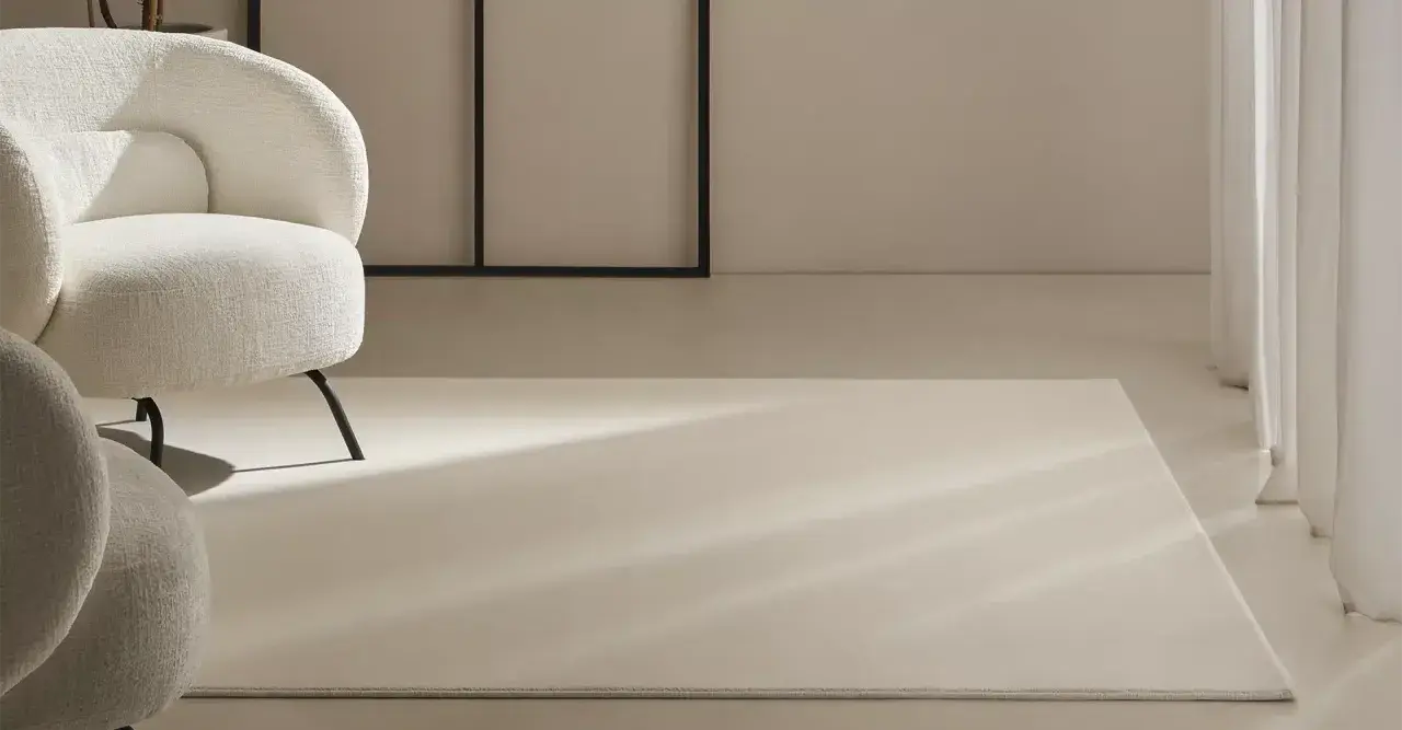Un espacio moderno con sillones blancos y alfombras de lana a medida, bañadas por la luz natural.