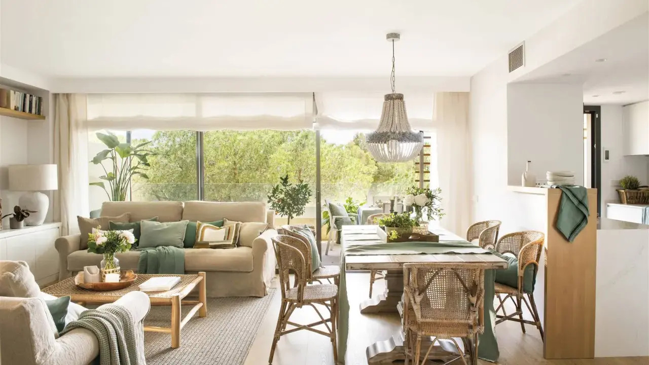 Elegante decoracion salon con sofás, mesa de comedor de madera, sillas de mimbre y gran ventanal con vistas al exterior.