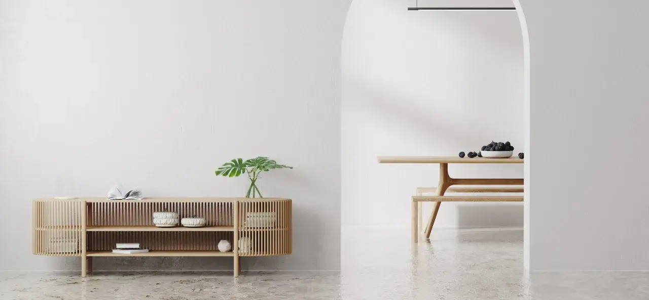 Un espacio minimalista con un aparador de madera y un comedor. Las paredes lisas y el suelo pulido crean un ambiente sereno.