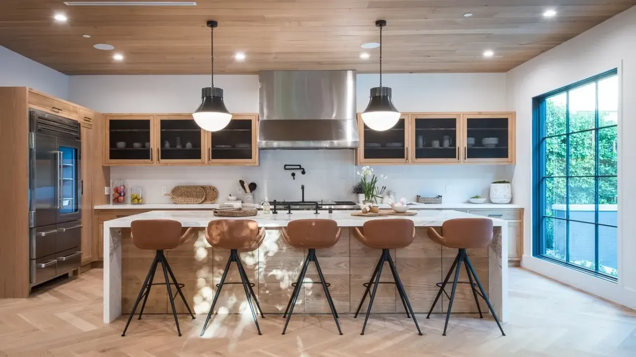 Cocina moderna con isla central y taburetes de cuero marrón. Las medidas del taburete son ideales para la altura de la isla.
