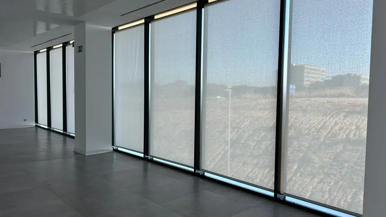 Ventanas con tejido screen que filtran la luz, creando un ambiente sereno en la oficina.