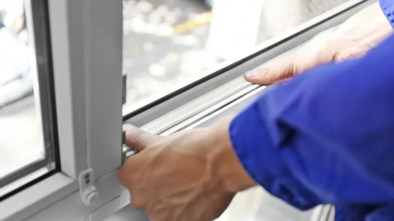 Manos ajustando el burlete para aislar ventanas, mejorando la eficiencia energética del hogar.