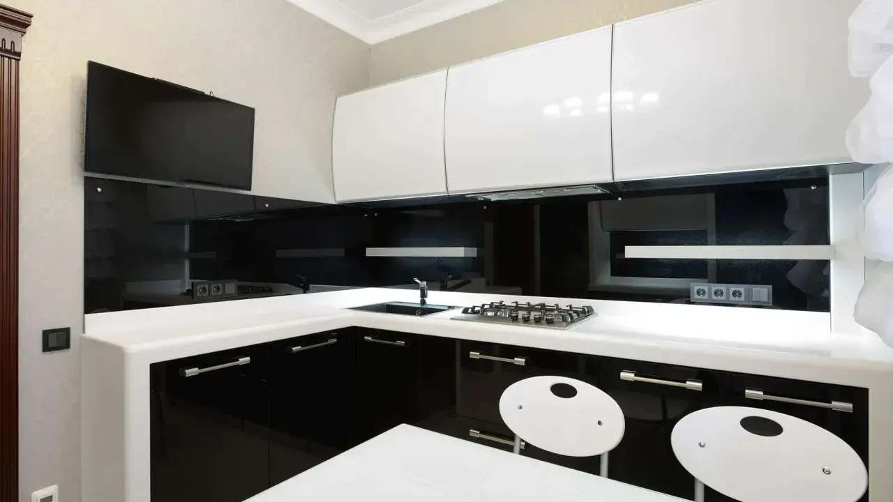 Elegantes cocinas en blanco y negro, con encimeras blancas, gabinetes negros brillantes y detalles modernos.