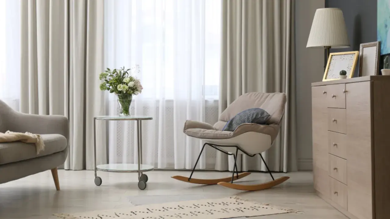 Elegantes cortinas de salón, mecedora beige y cómoda de madera. Las últimas tendencias en cortinas para tu salón.