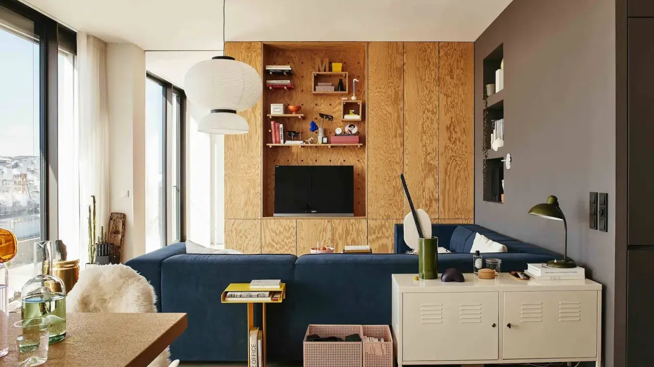 Un salón moderno con sofá azul, estanterías de madera y lámparas colgantes. Un espacio acogedor para **tini living**.