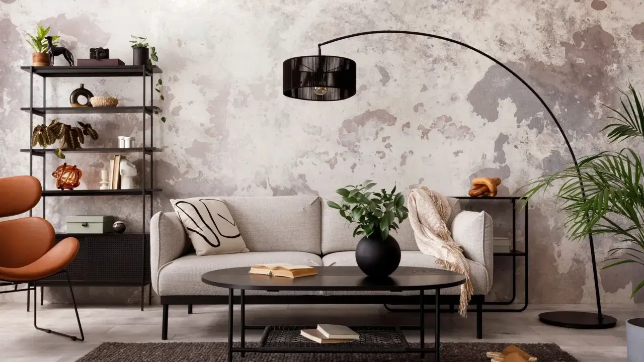 Sofá gris, mesa negra y estantería metálica en una sala con decoración estilo industrial chic. Pared texturizada y silla naranja.
