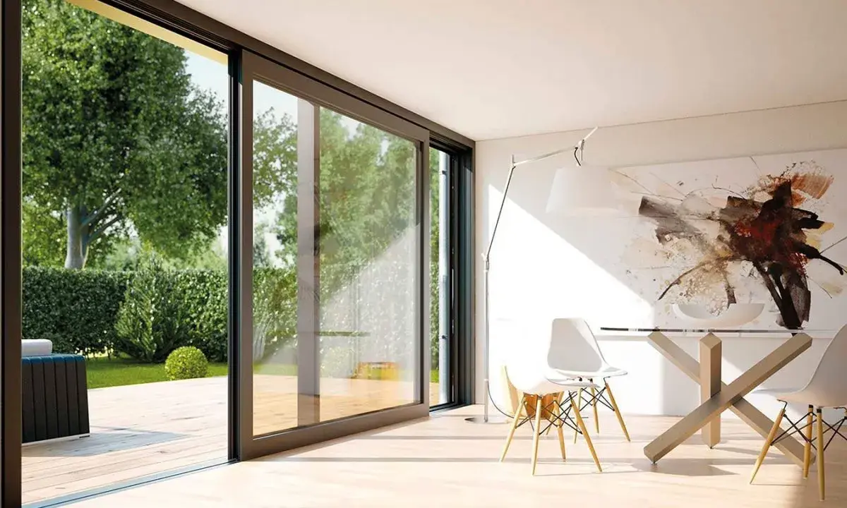 Amplias ventanas aislantes conectan un moderno comedor con un exuberante jardín.