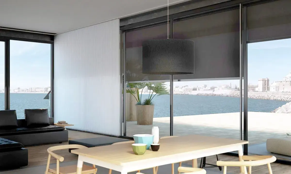 Comedor moderno con vistas al mar, decorado con estores Bandalux que controlan la luz.