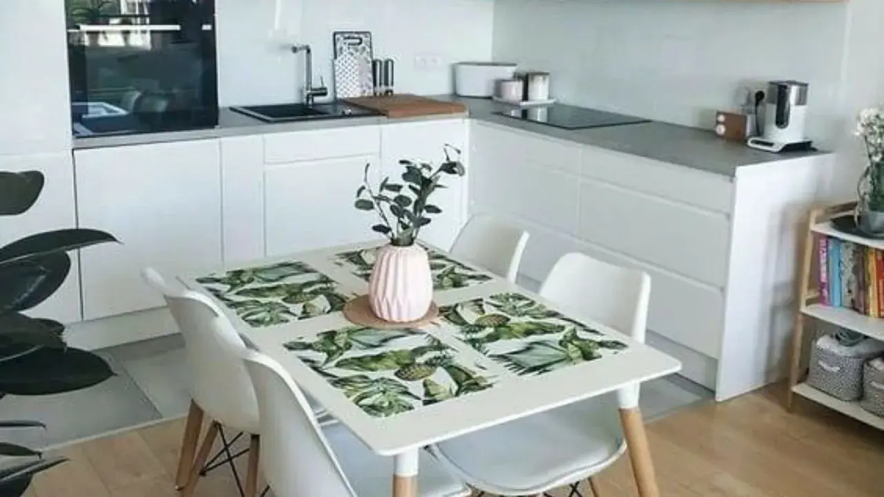 Cocinas pequeñas con mesa para comer, un espacio funcional y moderno con encimeras blancas, electrodomésticos integrados y una mesa con mantel tropical.