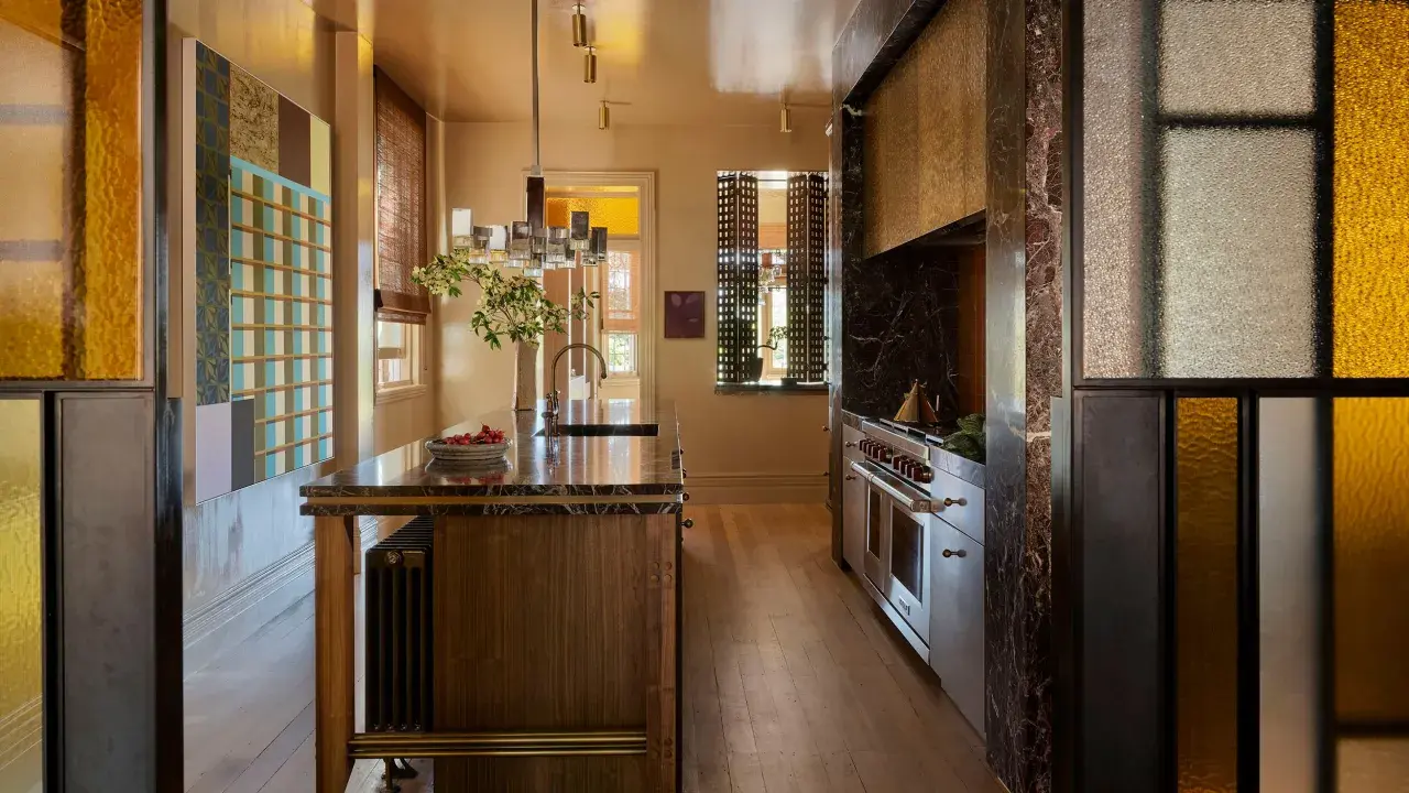 Cocina de lujo con isla de mármol, electrodomésticos de acero inoxidable y detalles en vidrio de colores. Una clara tendencia en cocinas modernas y sofisticadas.