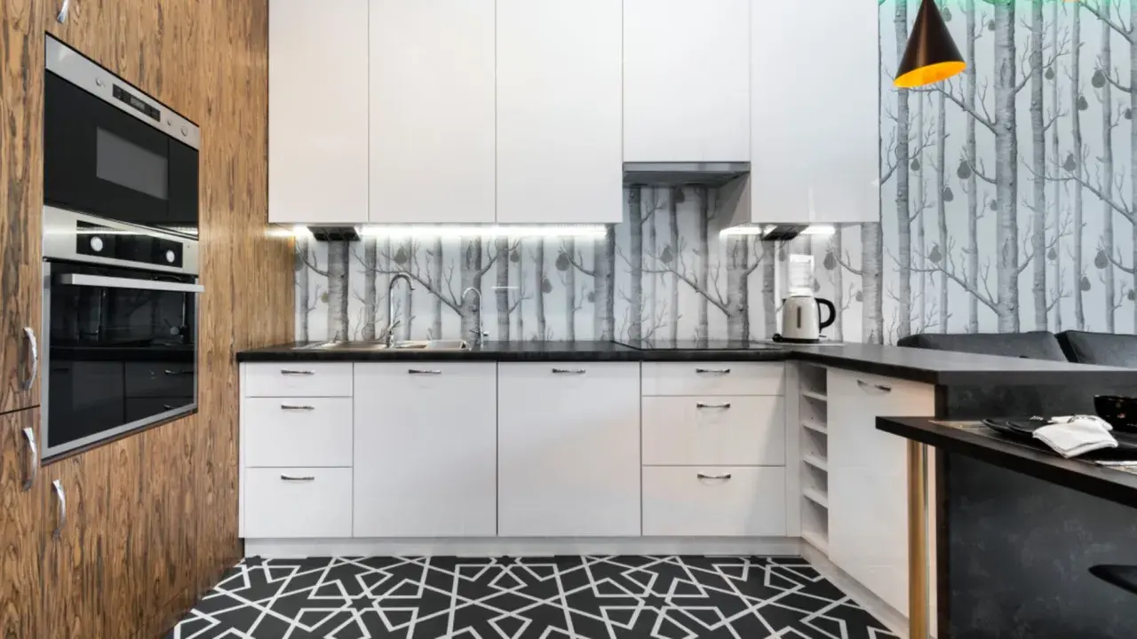 Cocinas modernas con papel pintado de árboles, gabinetes blancos y suelo geométrico.