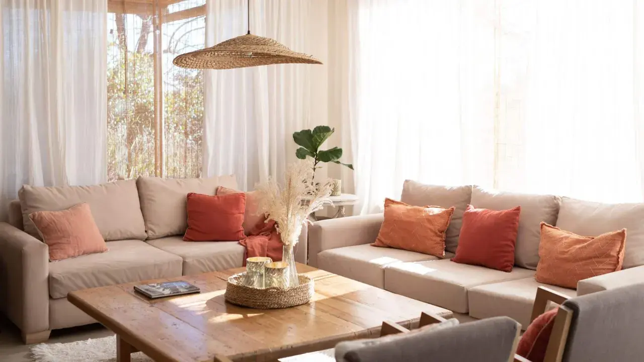 Salones pequeños con encanto: sofás beige, cojines terracota y naranja, mesa de madera, plantas y luz natural.