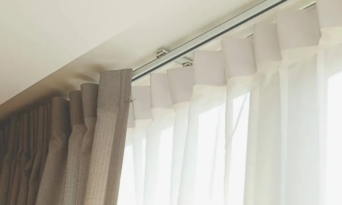 Detalle de rieles para cortinas, mostrando diferentes tipos de tela y su sistema de sujeción al techo.