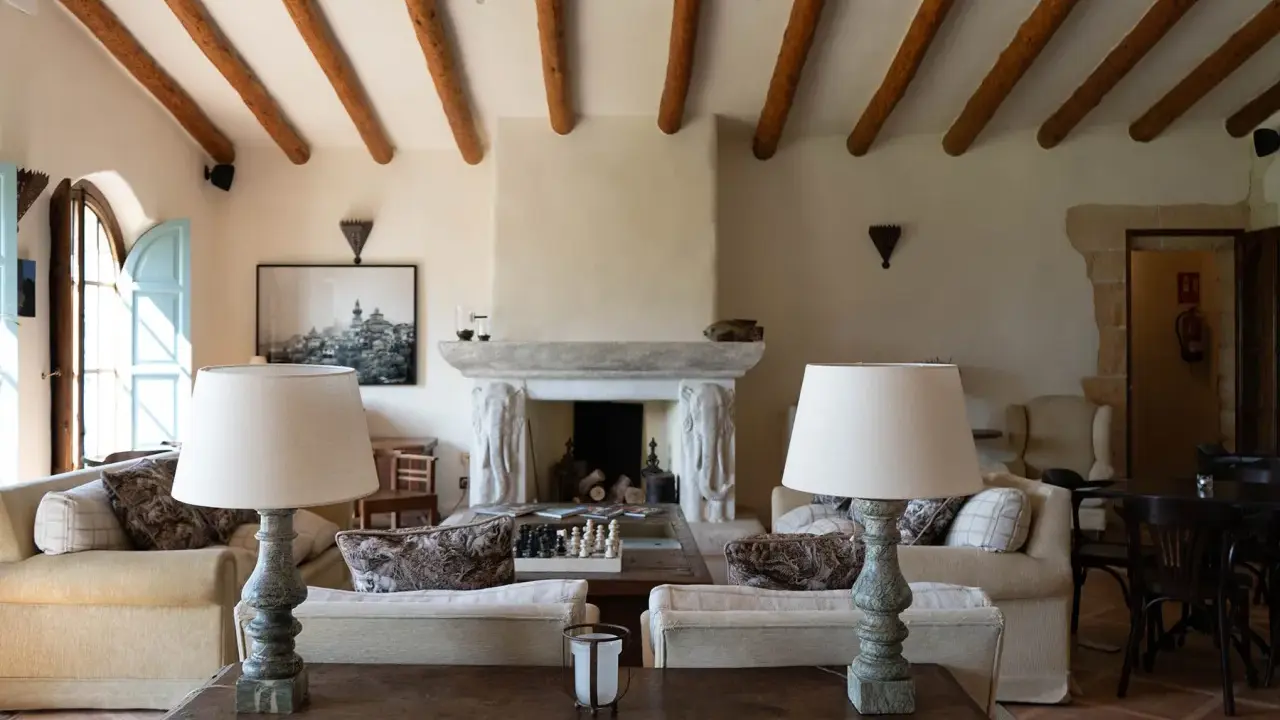Acogedor salón comedor de casa de campo con vigas de madera, chimenea de piedra y sofás confortables.