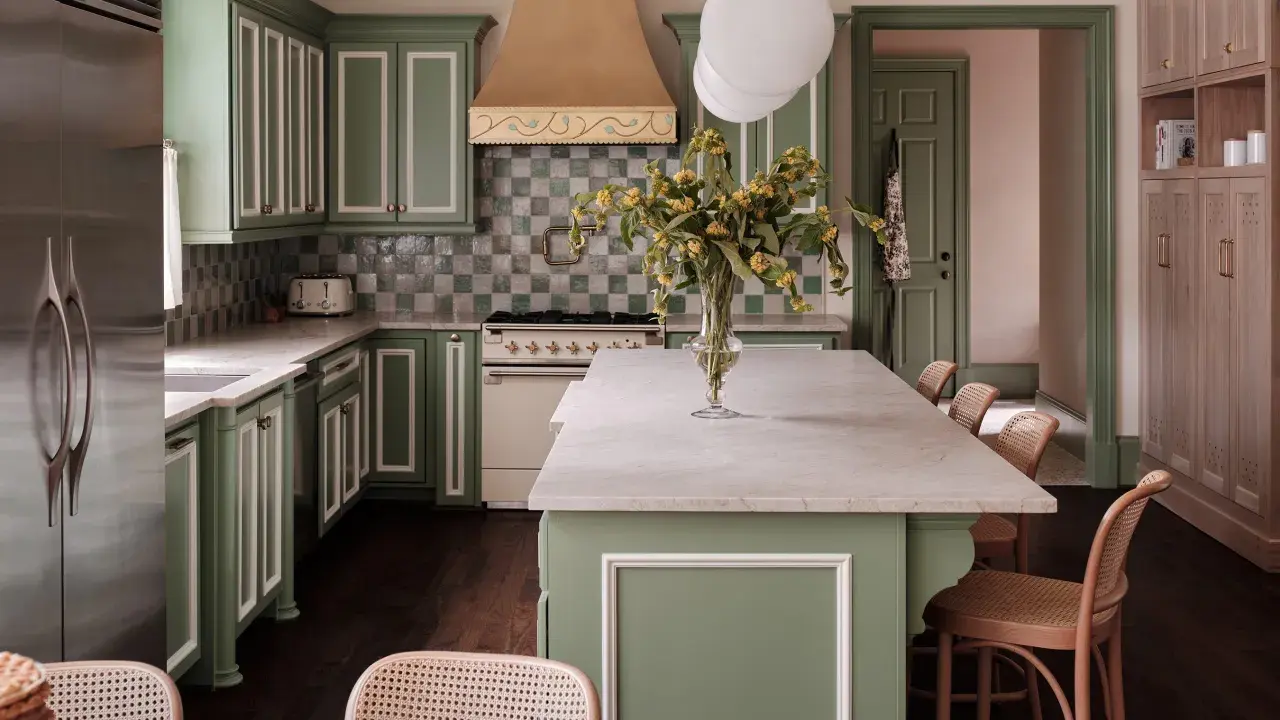 Elegantes cocinas verdes con gabinetes de madera clara, encimeras de mármol y un toque de color en la campana de la estufa.