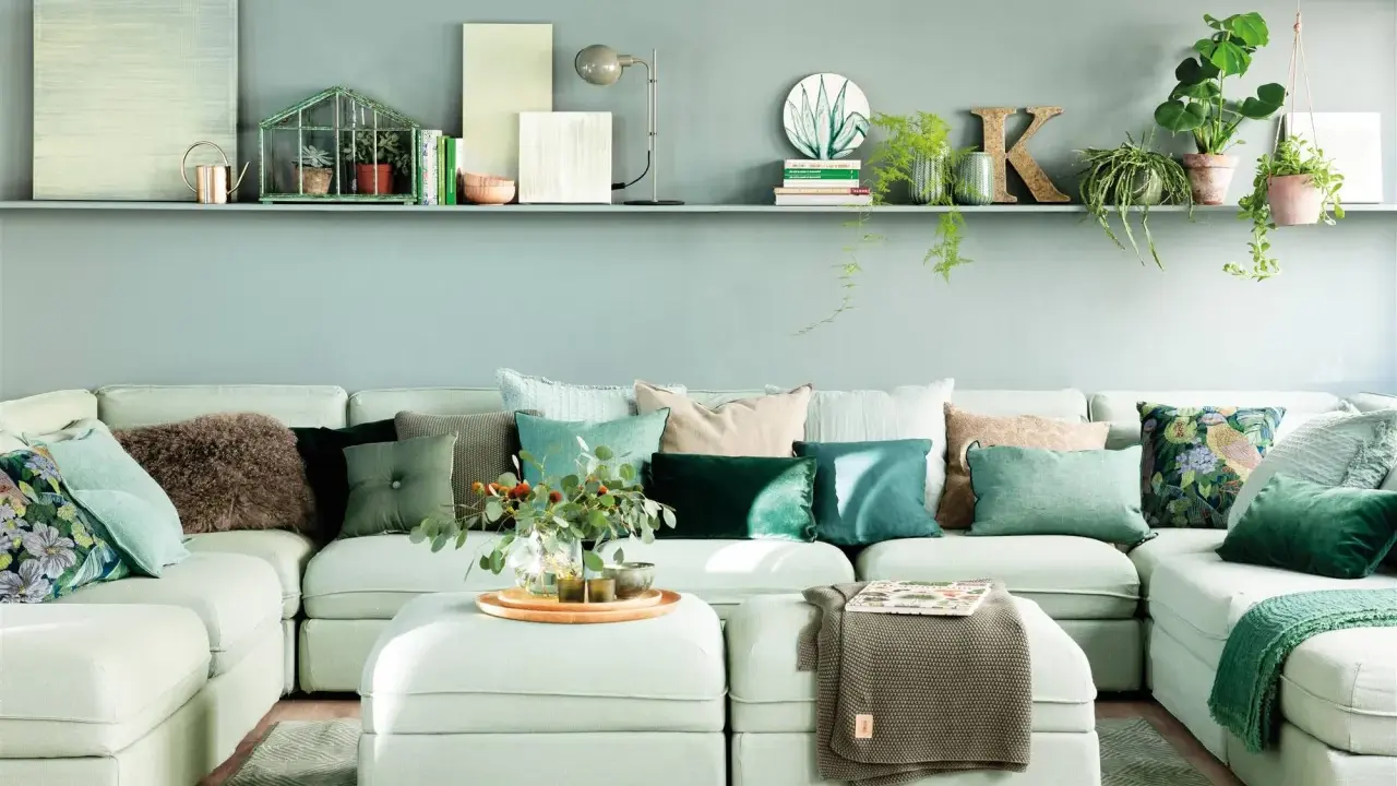 Sofá modular verde agua con cojines en tonos tierra y verdes, creando un ambiente sereno.