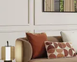 Cojines decorativos de sofá en tonos tierra y un diseño geométrico, junto a una lámpara.