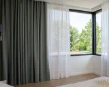 Cortinas bandalux grises y blancas en un dormitorio moderno, con vistas a un jardín frondoso.