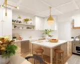 Cocina moderna con isla central, gabinetes blancos y detalles dorados. Ideas para como diseñar una cocina funcional y elegante.
