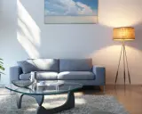 Sofá gris oscuro, mesa de cristal, alfombra mullida y lámpara de pie. Un espacio acogedor para relajarse.