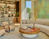 Sofá curvo y sillones de diseño contemporáneo, estanterías llenas de libros y arte abstracto en un salón luminoso.
