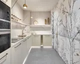 Cocinas pequeñas con encanto: gabinetes color crema, encimeras de mármol, electrodomésticos Siemens y un papel tapiz de bosque invernal.