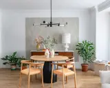 Comedor con mesa redonda de madera, sillas de cuero, lámpara moderna y plantas. Ideal para decorar piso moderno y elegante.