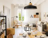 Acogedor salón estilo nórdico con sofá, sillón de mimbre, mesa de centro y estantería negra.