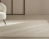 Un espacio moderno con sillones blancos y alfombras de lana a medida, bañadas por la luz natural.