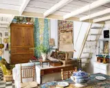 Un acogedor salón con estilo cottagecore, lleno de textiles coloridos, muebles de madera y objetos vintage.