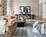 Elegante sala de estar con sofás blancos, mesa de centro negra y alfombras a rayas que complementan la decoración de la casa.