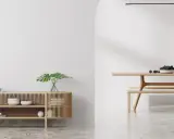 Un espacio minimalista con un aparador de madera y un comedor. Las paredes lisas y el suelo pulido crean un ambiente sereno.