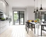 Cocina moderna con encimera de mármol negro y **suelos para cocinas sin obras** de madera clara. Mesa de comedor con sillas negras y chimenea.