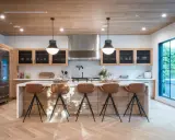 Cocina moderna con isla central y taburetes de cuero marrón. Las medidas del taburete son ideales para la altura de la isla.