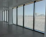 Ventanas con tejido screen que filtran la luz, creando un ambiente sereno en la oficina.