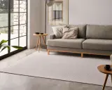 Elegante salón con sofá gris y alfombra de patrones geométricos, mostrando diversos tipos de alfombras para un hogar acogedor.