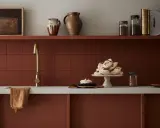 Encimera de cocina pintada en tono terracota, con grifería dorada y detalles decorativos.