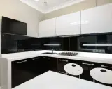 Elegantes cocinas en blanco y negro, con encimeras blancas, gabinetes negros brillantes y detalles modernos.