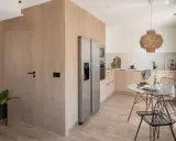 Elegante decoracion comedor pequeño con mesa redonda de cristal, sillas negras y cocina integrada.
