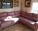 Cómodo sofá rinconera rosa, ideal para decorar salón. En la pared, un cuadro de nudos marineros y pinturas.