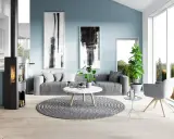 Sala de estar moderna con paredes de color azul polvoriento, sofá gris, chimenea y arte abstracto.