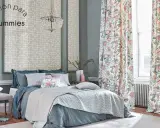 Cama elegante con ropa de cama azul y cojines florales, cortinas de proteas y papel tapiz geométrico. Un kilim Maimana aportaría calidez a este espacio.