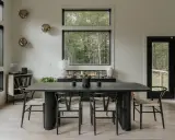 Salón moderno con mesa de comedor negra, sillas de madera y decoración de pared con esferas doradas.